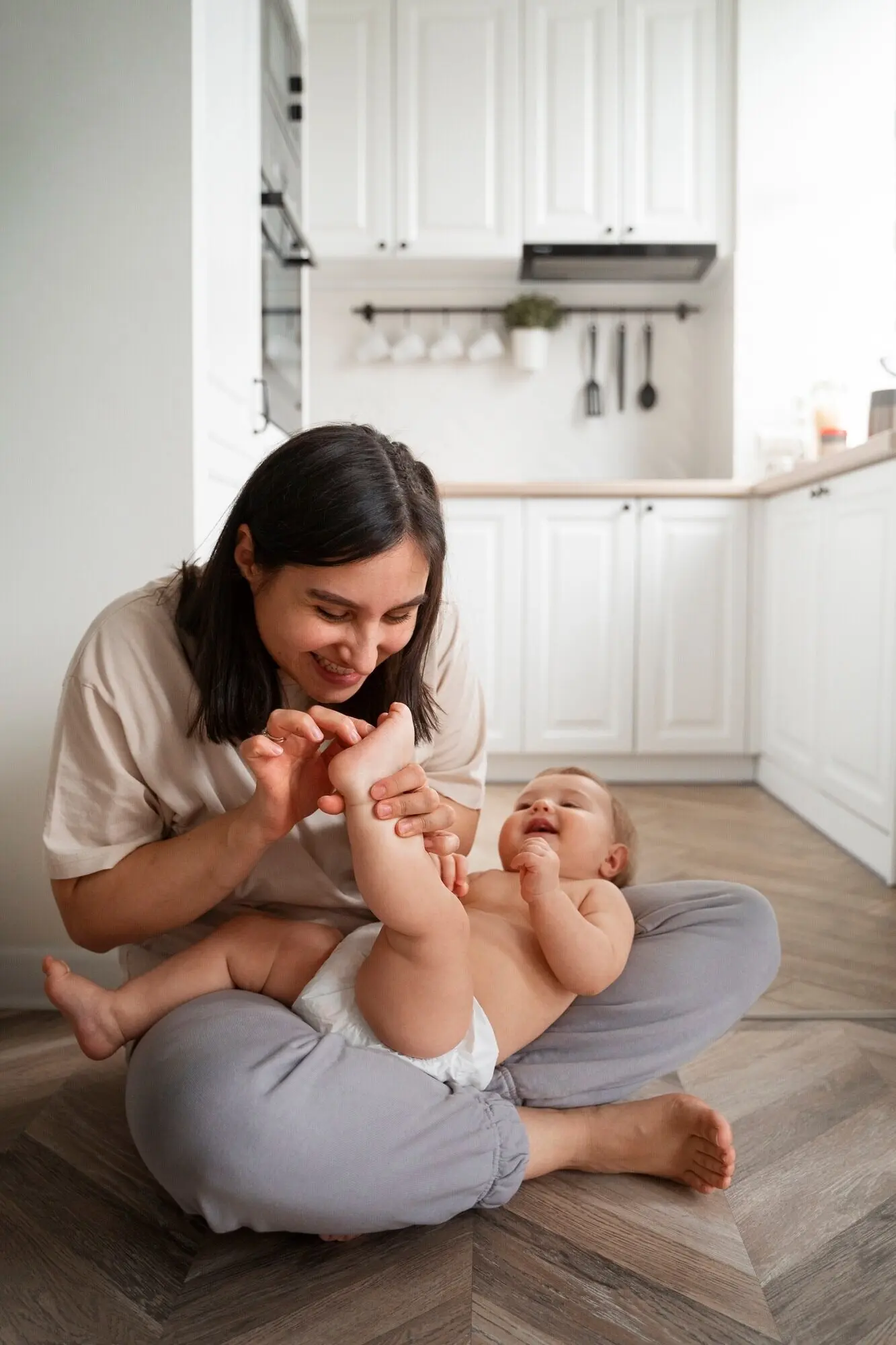 Полный план: мать щекочет ступню младенца.